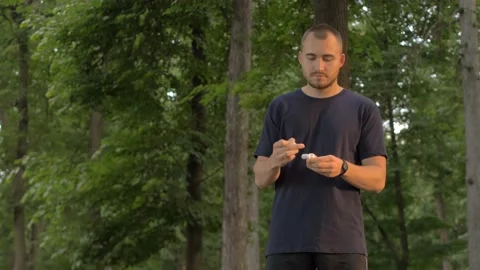 Man inserts wireless headphones in the park and listens to music Stock Footage 91831198