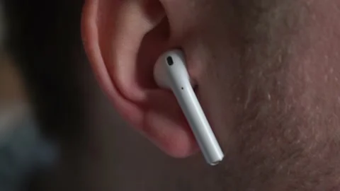 Man inserts a wireless headset into his ears, listens to music, shakes his head Stock Footage 154843713