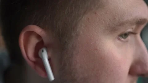 Man inserts a wireless headset into his ears, listens to music, shakes his head Stock Footage 154843846