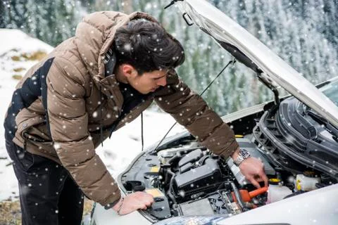 Man inspecting car engine in the snow Stock Photos