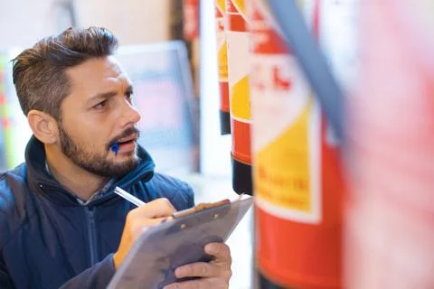Man inspecting fire extinguishers Stock Photos