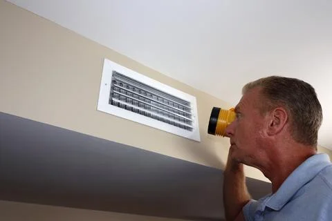 Man Inspecting a Home Rectangle Wall Air Vent with a Flashlight Stock Photos
