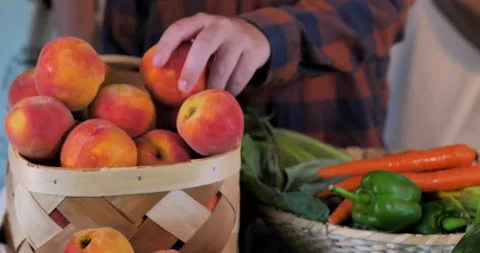 Man inspecting peaches and assorted vegetables at farmer's market. Video stock 138332516