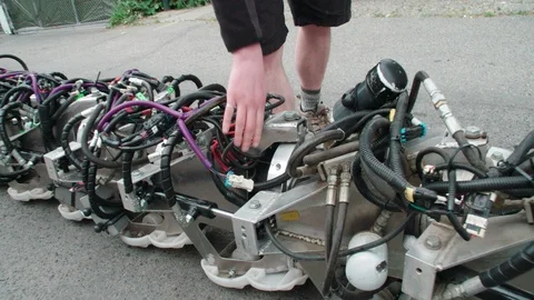 Man inspecting robotic snake in road Stock Footage 93578833