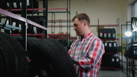 Man inspecting a tire before purchase in auto parts store Stock Footage 301549602