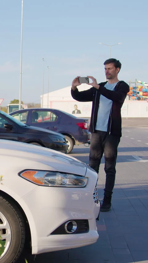 Man inspecting used car condition outdoors, checking details with smartphone Stock Footage 318475939
