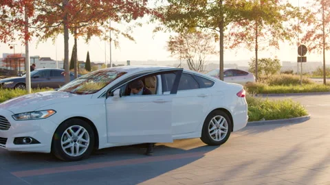 Man inspecting a white sedan before purchasing, standing beside the open door Stock Footage 315529581