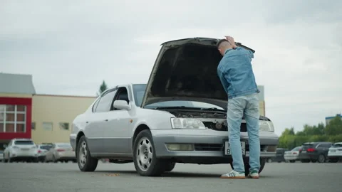 Man inspects broken car, Tense man checks vehicle exterior, Stranded driver Stock Footage 333651022