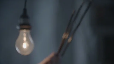 Man Inspects Crossbow Arrows by Single Lightbulb HD Video Stock Footage 90386034