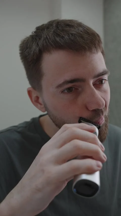 Man inspects reflection. Check out tidy beard under warm bathroom glow Видео 333332133