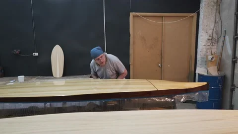 Man inspects the surface of the Surf Board Stock Footage 132168455