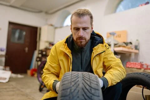 Man inspects a tire in a garage while preparing for maintenance work on a Photos