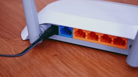 Man install Ethernet network Patch Cable on router. Wireless Router On The Desk Video stock 157890060