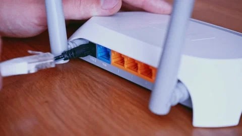 Man install Ethernet network Patch Cable on router. Wireless Router On The Desk Video stock 157890262