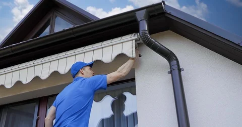 Man installing and checking awning on house facade wall over the balcony window Stock Footage 128959059