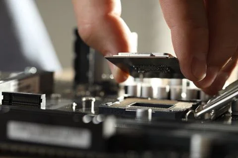 Man installing computer chip onto motherboard at table, closeup Stock-Fotos