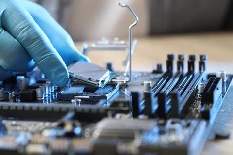 Man installing computer chip onto motherboard at table, closeup Foto stock