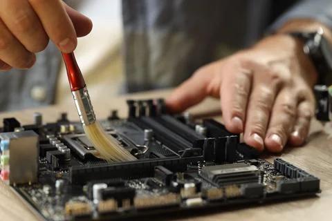 Man installing computer chip onto motherboard at wooden table, closeup Stock-Fotos