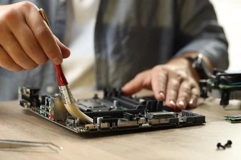 Man installing computer chip onto motherboard at wooden table, closeup Stock-Fotos