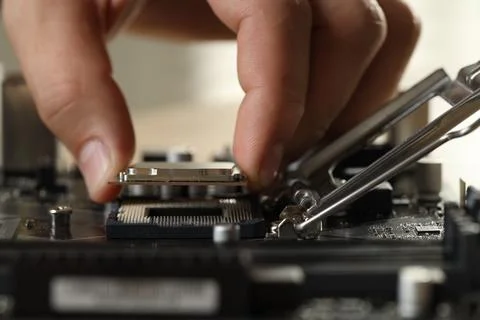 Man installing computer chip onto motherboard at table, closeup Stock-Fotos
