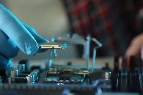 Man installing computer chip onto motherboard at table, closeup Stock-Fotos