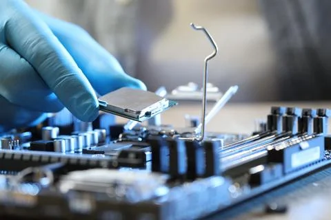 Man installing computer chip onto motherboard at wooden table, closeup Stock-Fotos