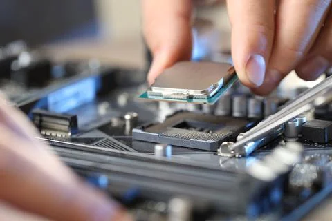 Man installing computer chip onto motherboard at table, closeup Foto stock