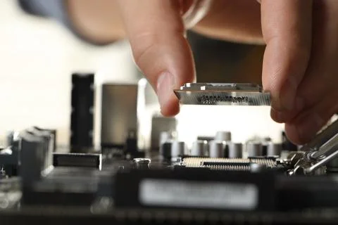 Man installing computer chip onto motherboard at table, closeup Foto stock