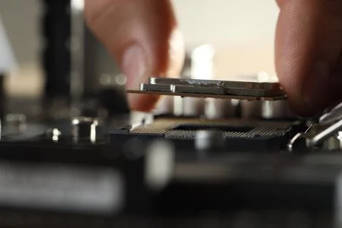 Man installing computer chip onto motherboard at table, closeup Stock-Fotos