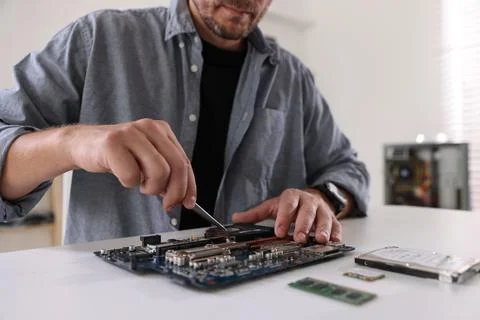 Man installing computer chip onto motherboard at white table, closeup Stock Photos