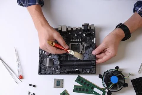 Man installing computer chip onto motherboard at white table, top view Stock-Fotos