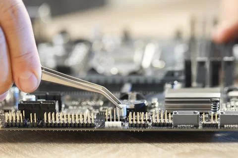 Man installing computer chip onto motherboard at wooden table, closeup Stock-Fotos