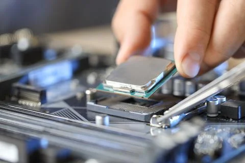 Man installing computer chip onto motherboard at table, closeup Stock-Fotos