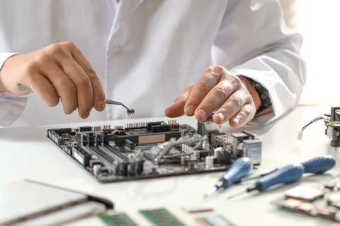 Man installing computer chip onto motherboard at white table, closeup Stock-Fotos