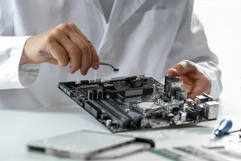 Man installing computer chip onto motherboard at white table, closeup Stock-Fotos