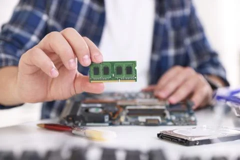 Man installing computer chip onto motherboard at white table, closeup Stock-Fotos
