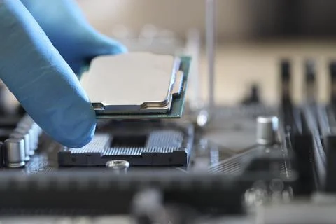 Man installing computer chip onto motherboard at table, closeup Stock-Fotos