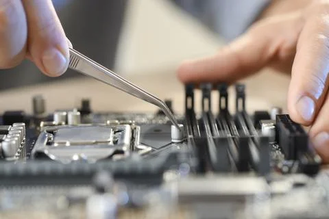Man installing computer chip onto motherboard at table, closeup Stock Photos