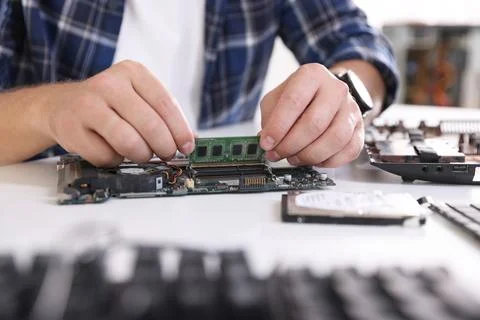 Man installing computer chip onto motherboard at white table, closeup Stock-Fotos