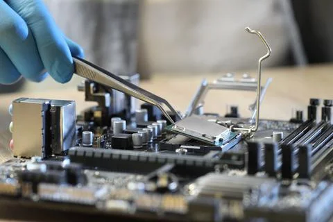 Man installing computer chip onto motherboard at table, closeup Stock-Fotos