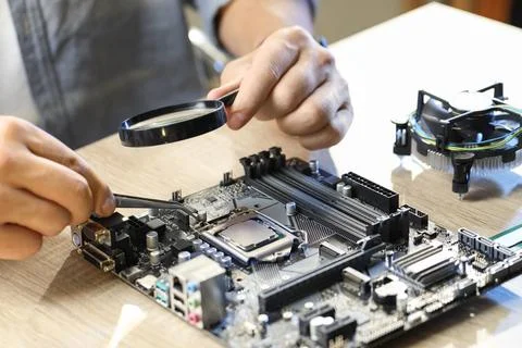 Man installing computer chip onto motherboard at wooden table, closeup Stock-Fotos