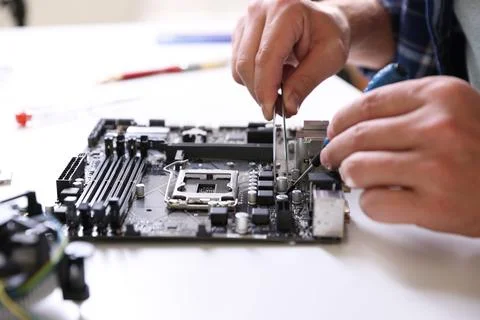 Man installing computer chip onto motherboard at white table, closeup Stock-Fotos