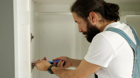 A man is installing the door on the wardrobe Stock Footage 145870818