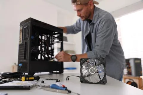 Man installing fan into computer at white table, selective focus Stock Photos