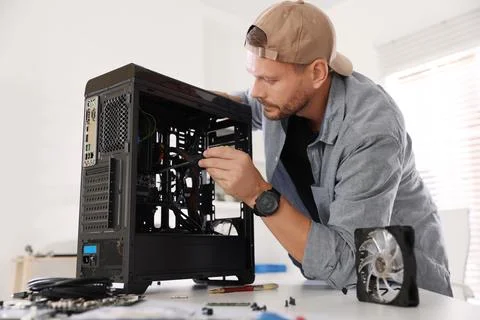 Man installing fan into computer at white table Stock Photos