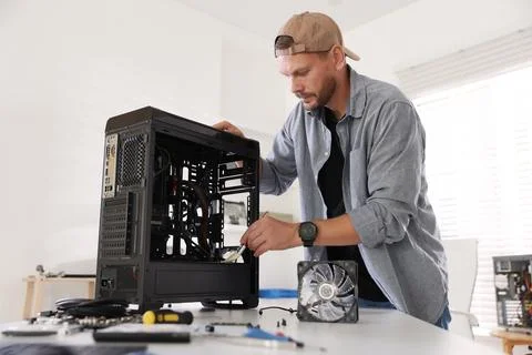 Man installing fan into computer at white table Stock Photos