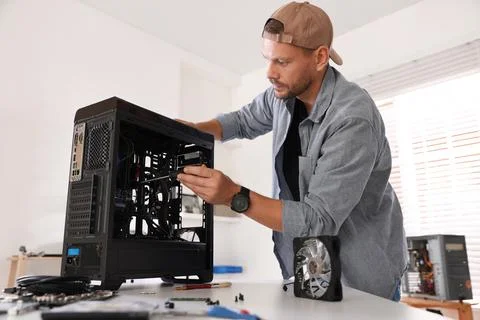 Man installing fan into computer at white table Stock-Fotos