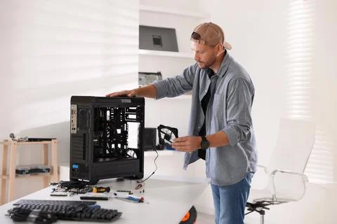 Man installing fan into computer at white table Stock Photos