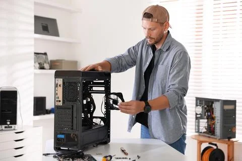 Man installing fan into computer at white table Foto stock