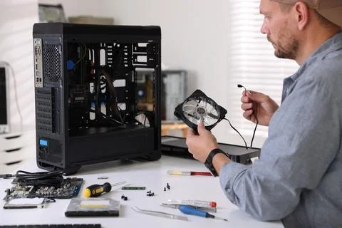 Man installing fan into computer at white table Stock Photos